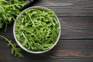 Fresh ripe green arugula leaves on dark wooden table, flat lay. Space for text
