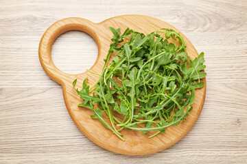 Fresh ripe green arugula leaves on light wooden table, top view