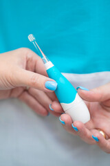 A hand holds a modern electric toothbrush in a wellarranged dental care setting