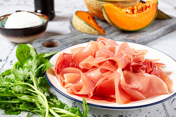 salad ingredients, prosciutto and melon, arugula and basil, mozzarella cheese, balsamic sauce, close-up,