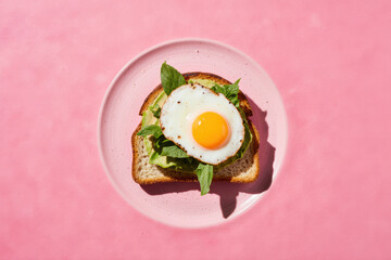 Avocado toast breakfast on pink backdrop.