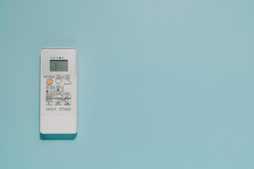 A white air conditioner remote control with digital display on light blue background with space for text. Perfect for themes of home comfort, climate control, and modern technology.