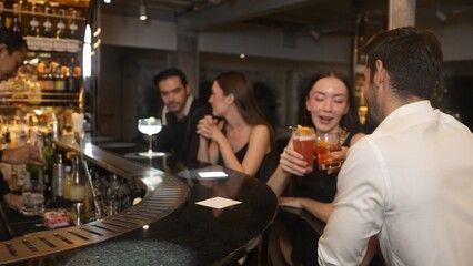 Couple making a toast with cocktail paloma and old fashioned at luxurious bar in lively conversation drinks celebrating a special party at vibrant nightclub while friend drinking Margarita. Vinosity.