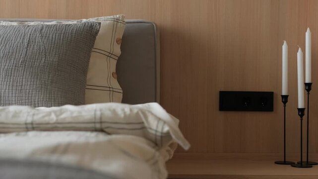 Cozy minimalist bedroom interior design with bed wooden headboard bed linen bedside table with candles. Modern furniture