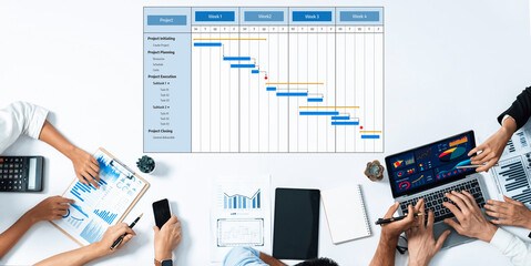 A team collaborates on project management with laptops and charts, showcasing Gantt charts and...