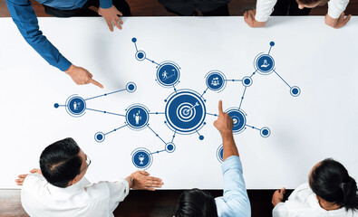 A diverse group of business professionals engaged in a brainstorming session, analyzing digital...