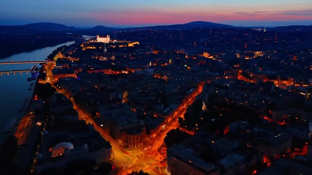 Beautifully lit streets in the old town of Bratislava, Slovakia. Drone footage at the dusk time. Bratislava Castle standing out at backdrop.