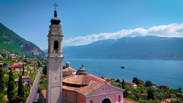 Aerial view of Salo, Italy with terracotta rooftops, lakeside promenade, and boats docked on the shore of Lake Garda on a sunny summer day