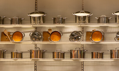 Stainless-steel saucepans and stockpots neatly lined on retail shelves