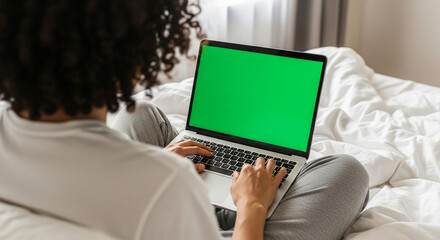 A person staring at a green screen of a laptop