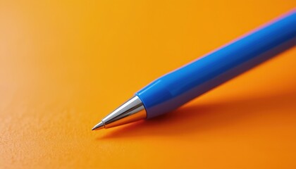 Blue pen lies on bright orange surface. Macro shot focuses on writing tool, its smooth plastic barrel and metallic tip. High contrast colors blue and orange create vibrant composition.