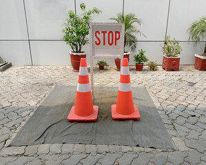 Outdoor Stop Zone with Orange Traffic Cones and Red STOP Sign on Gray Mat