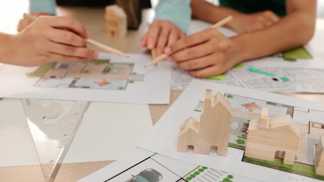 Smart architect and safety engineer discussion about building blueprint on table with architectural document, measurement tools and wooden block scatter around at modern office. Closeup. Delineation.