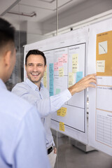 Two happy teammates laughing while reviewing creative ideas, working on joint project or insights...
