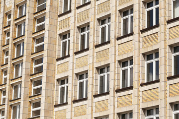 Facade of apartment building. Rows of windows yellow brick wall. Urban architecture with repeating...
