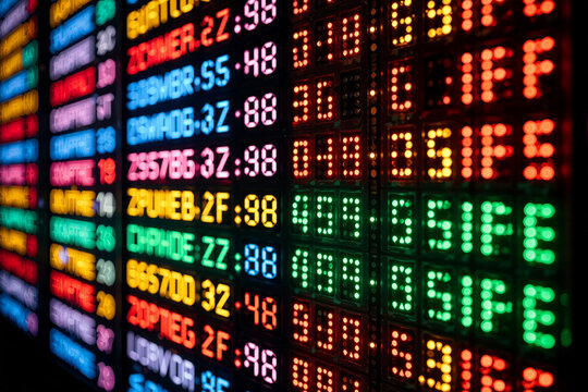 Bright electronic ticker display showing stock market data at a financial district location during busy trading hours