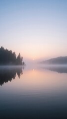 Serene lake view with soft fog and soft sunrise colors.