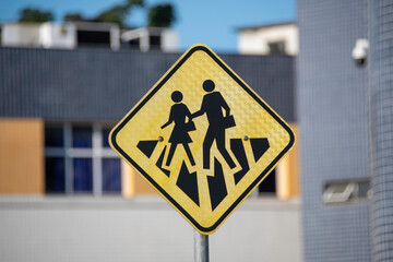 A sign alerting drivers to school crossings and student traffic. It indicates areas near schools, requiring extra attention and a reduced speed.
