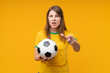 Serious young female soccer fan or player holding a football and pointing at the camera with accusing expression