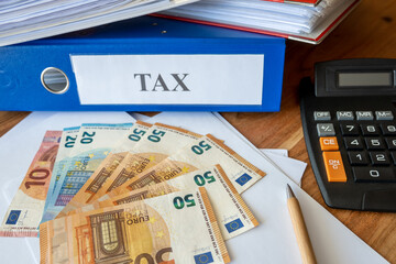 Much folders with tax paper, money bills, pen and calculator on the table.