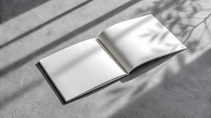 Open blank book resting on a textured surface with dramatic light and shadow patterns
