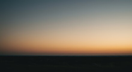 Fototapeta premium A serene sunset sky over a dark landscape