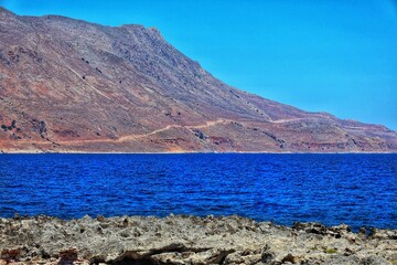 Scenic rocky coast and dry mountain with deep blue sea under a clear summer sky in western Crete,...