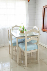 Bright dining area with white table, blue chairs and flower centerpiece