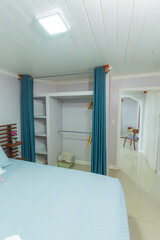 Organized bedroom closet with hangers, shelves and blue curtains