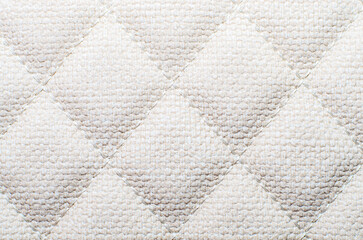 Soft light beige quilted fabric texture with diamond pattern creating cozy background