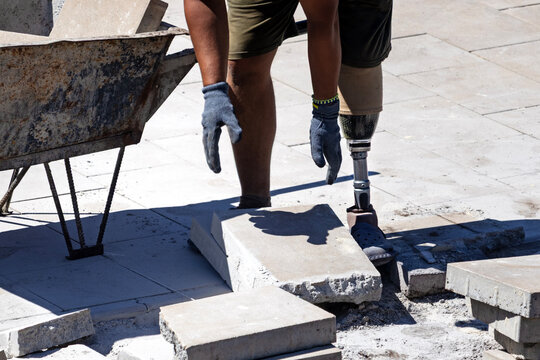 A man with a prosthetic leg works on a construction site. Prosthetic leg.	