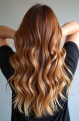 Obraz premium Back view of woman with long wavy ombre hair. Shades of brown transition to blonde. Healthy, shiny hair texture. Perfect hairstyle for fashion, beauty, salon.