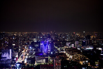 An enchanting aerial night view of a bustling Bangkok city, showcasing illuminated highways and towering buildings under a dark sky.