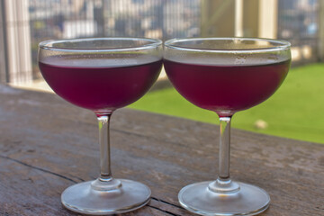 Two elegant glasses of red wine sit on a wooden surface