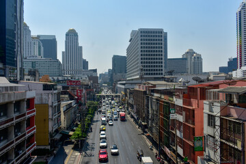 Busy city street with traffic and modern skyscrapers under a clear sky in Bangkok, Thailand.