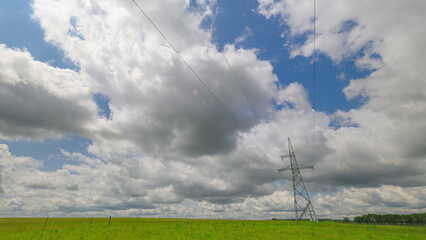 Electricity pylon or high voltage power line, black contour, on the background of the cloudy sky.
