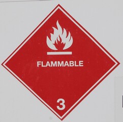 The red sign has a flame and the word flammable on its face. At the bottom the number three. A...