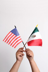 Hands holding flags of Mexico and the United States as a representation of international relations between the governments of the countries