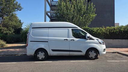 Efficient urban delivery vehicle parked on city street near modern apartment. White delivery van on...