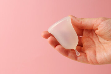 Eco-friendly menstrual cup in female hands on bright background