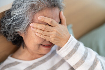 Stressed Asian senior woman got headache or eye strain. Loneliness depressed elderly woman crying....