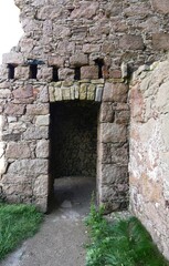 A weathered stone doorway set into the thick walls of an ancient castle ruin