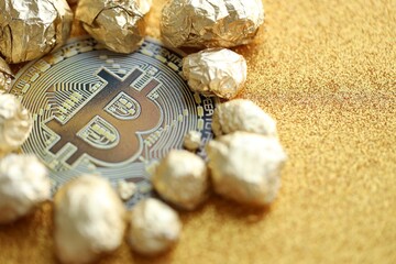 Small pile of golden nuggets and bitcoin cryptocurrency coin on shiny gold glitter background