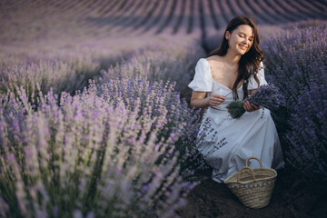 Woman picking lavender in a large field of purple flowers