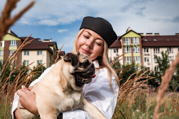 Young happy beautiful woman holds her beloved dog in her arms. Dog walking. Street photography.