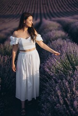 Young woman walking and caressing lavender flowers in a field