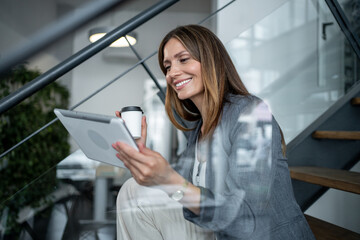 Businesswoman using digital tablet and drinking coffee on stairs
