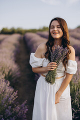 Woman wearing white dress holding lavender bouquet in a lavender field