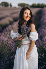 Woman wearing white dress holding lavender bouquet in a lavender field