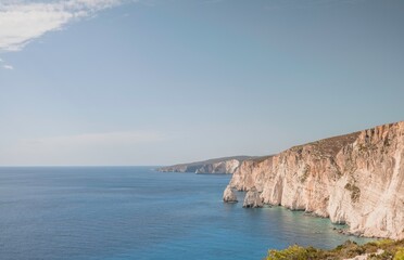 Sunlit cliffs tower over crystal clear turquoise waters on the Island of Zakynthos, Greece,...